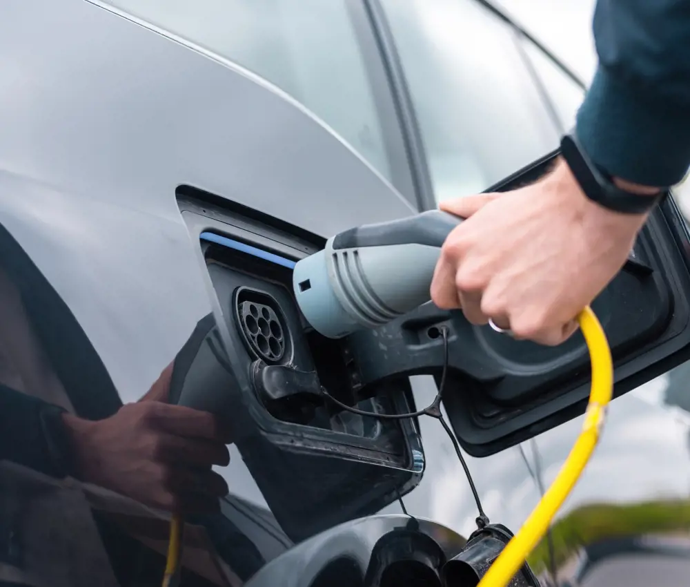 Man Plugging Charger Into Electric Car Charge Station
